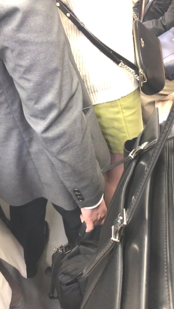 男性の鞄が女性のスカートの下の方にあるのを映した画像
